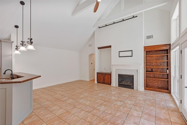 unfurnished living room with visible vents, a sink, lofted ceiling with beams, a fireplace, and baseboards