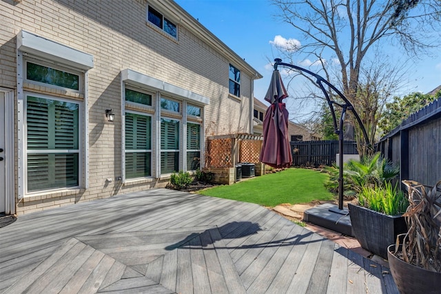 deck with a yard, central air condition unit, and a fenced backyard