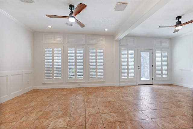 empty room featuring visible vents, crown molding, a decorative wall, and a ceiling fan