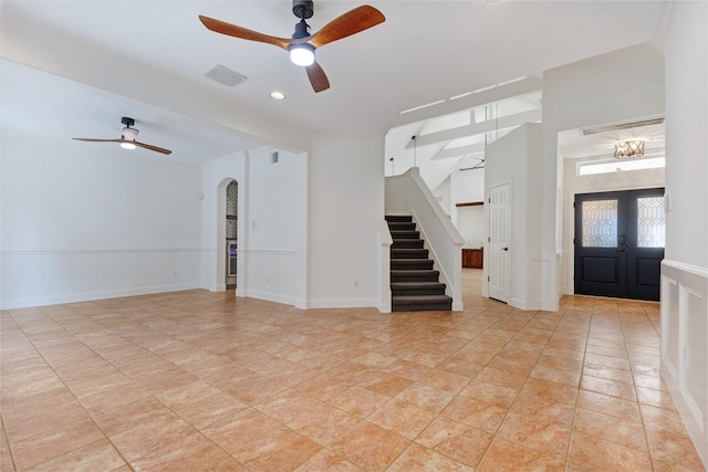 empty room featuring light tile patterned floors, baseboards, ceiling fan, stairs, and french doors