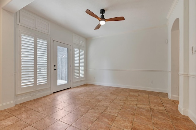 empty room featuring crown molding, light tile patterned flooring, baseboards, and ceiling fan