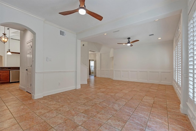 unfurnished room featuring visible vents, arched walkways, crown molding, a decorative wall, and ceiling fan