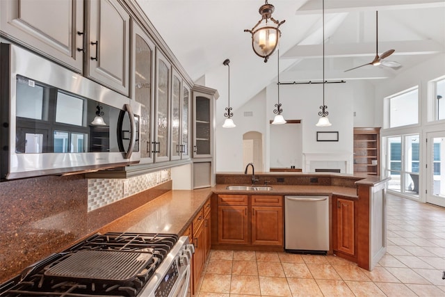 kitchen with glass insert cabinets, brown cabinetry, arched walkways, stainless steel appliances, and a sink