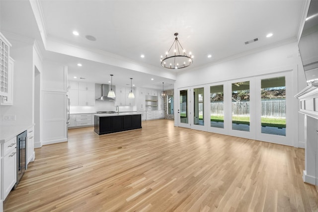 unfurnished living room featuring visible vents, wine cooler, a chandelier, and crown molding