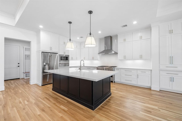 kitchen featuring high quality appliances, a sink, wall chimney range hood, white cabinets, and light countertops