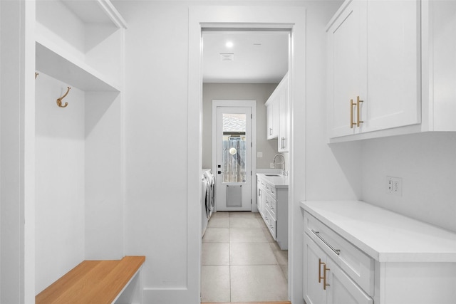 laundry area featuring washer and clothes dryer, laundry area, light tile patterned floors, and a sink