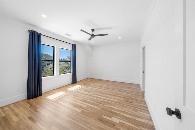 spare room with crown molding, a ceiling fan, visible vents, and light wood finished floors