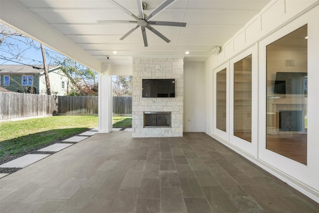 view of patio with a ceiling fan, an outdoor stone fireplace, and a fenced backyard