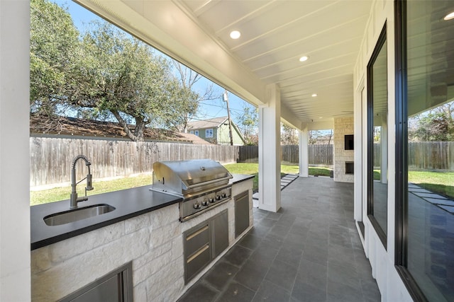 view of patio / terrace with an outdoor kitchen, area for grilling, a fenced backyard, and a sink