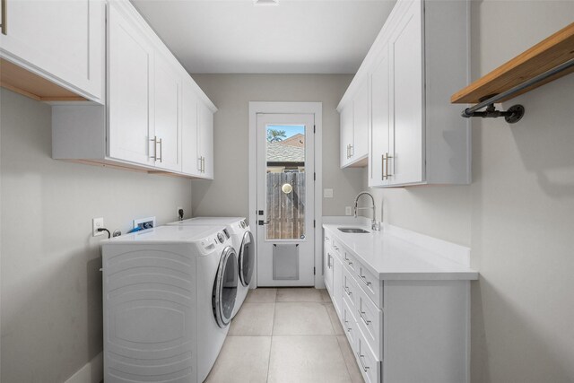 laundry area with a sink, cabinet space, independent washer and dryer, and light tile patterned floors