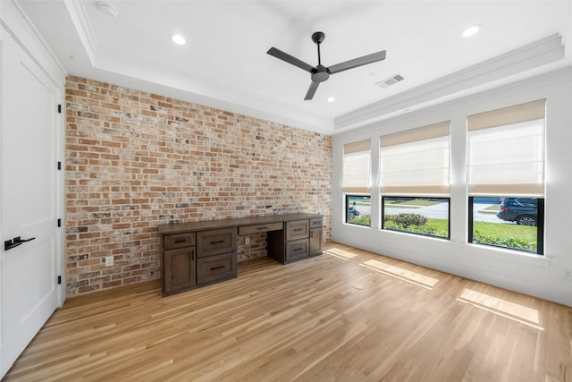 unfurnished office featuring crown molding, brick wall, light wood-type flooring, and ceiling fan