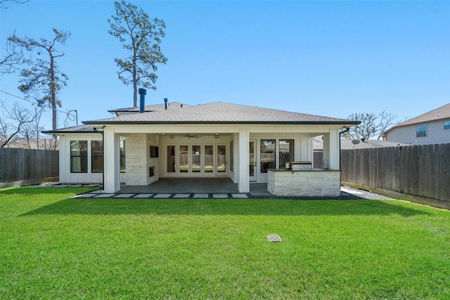 back of property featuring ceiling fan, roof with shingles, a lawn, a fenced backyard, and a patio