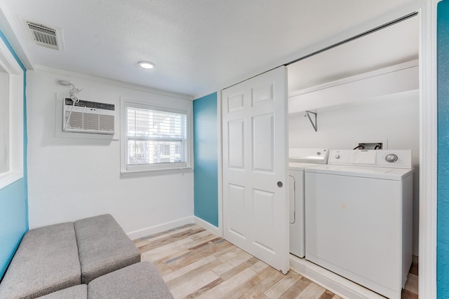 washroom with laundry area, visible vents, washing machine and clothes dryer, a wall mounted air conditioner, and light wood-type flooring