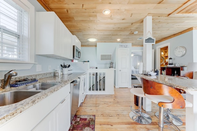 kitchen featuring white cabinets, wood ceiling, stainless steel appliances, and a sink