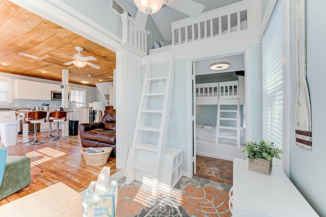 living area featuring visible vents, ceiling fan, light wood-type flooring, and wood ceiling