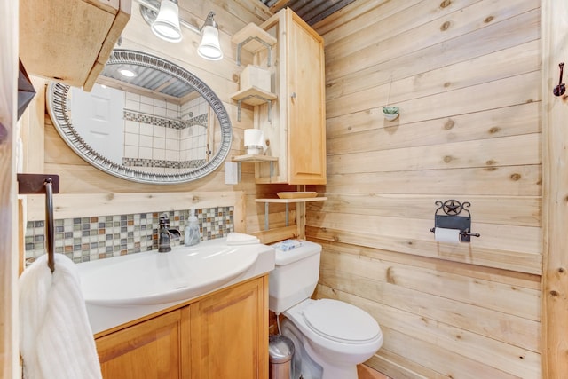 bathroom featuring tasteful backsplash, wood walls, vanity, and toilet