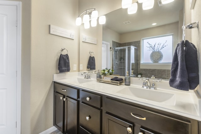 bathroom featuring double vanity, a stall shower, and a sink