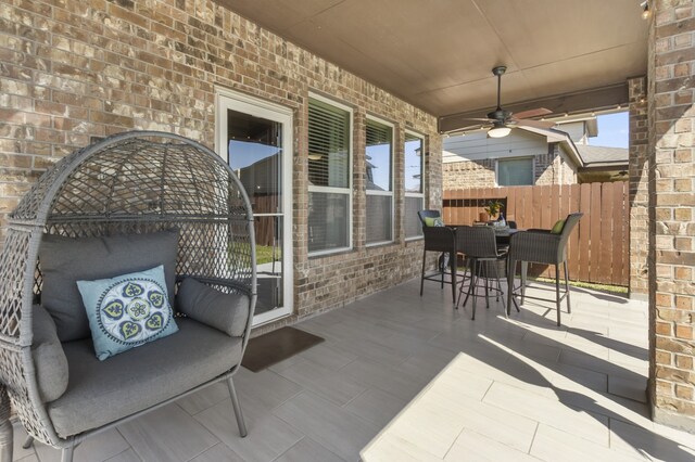 view of patio with outdoor dining space, ceiling fan, and fence