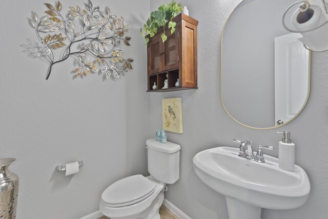 half bath with a sink, baseboards, and toilet