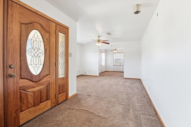 foyer entrance featuring light carpet, a ceiling fan, and baseboards