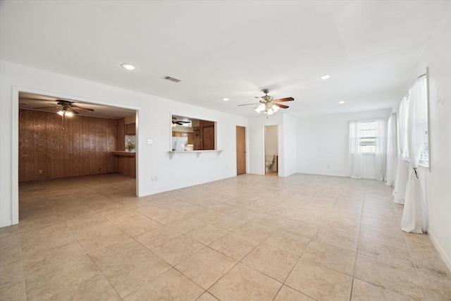 empty room featuring ceiling fan, light tile patterned flooring, recessed lighting, wood walls, and visible vents