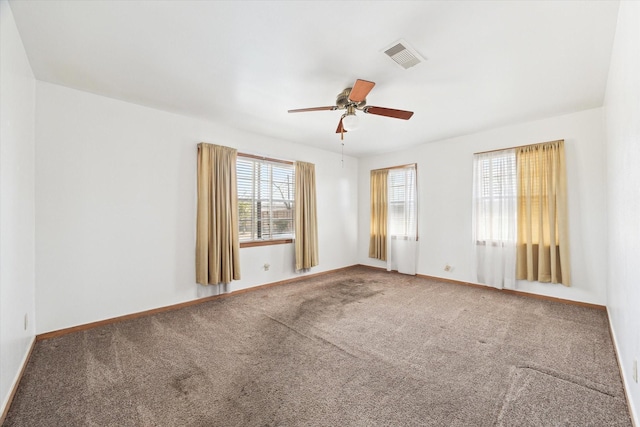 carpeted spare room featuring visible vents, ceiling fan, and baseboards