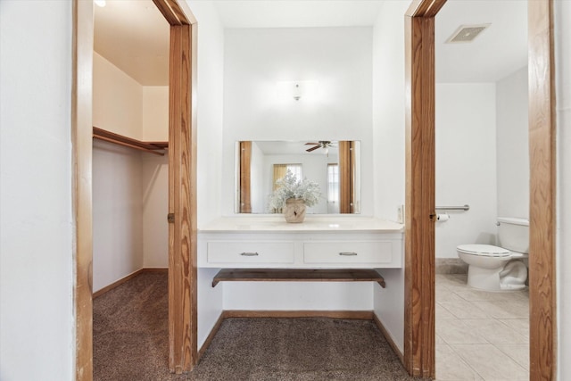 bathroom featuring baseboards, visible vents, toilet, tile patterned floors, and vanity