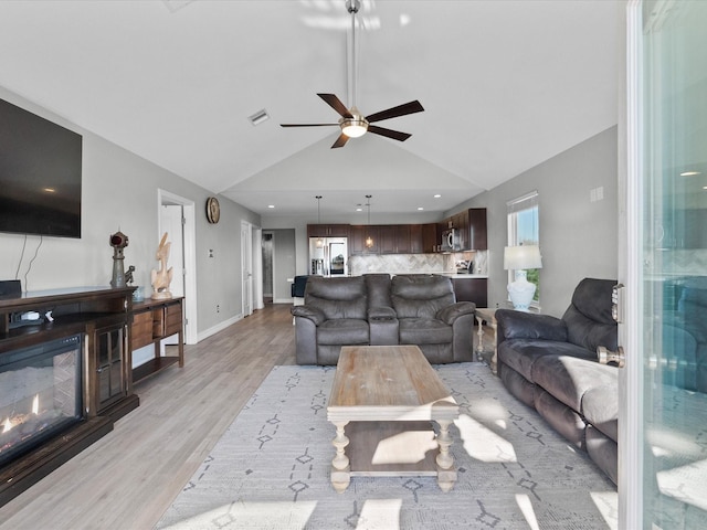 living area with ceiling fan, visible vents, baseboards, light wood finished floors, and a glass covered fireplace