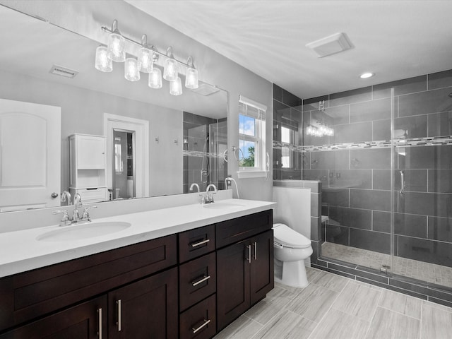 full bathroom featuring double vanity, a stall shower, a sink, and toilet