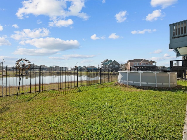 view of yard featuring a water view, fence, and a fenced in pool