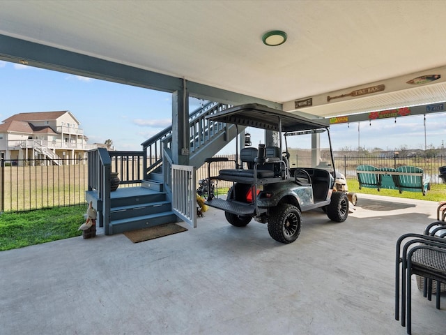 view of parking / parking lot featuring stairway, fence, and a carport