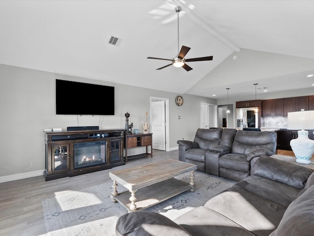 living area featuring light wood-style floors, a glass covered fireplace, visible vents, and baseboards