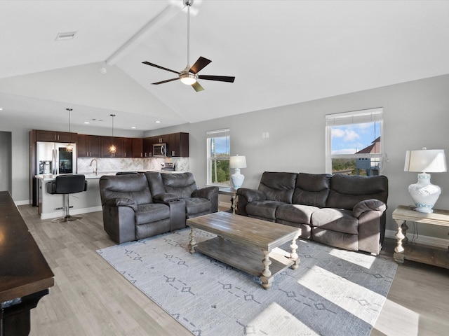 living area with baseboards, ceiling fan, beamed ceiling, light wood-type flooring, and high vaulted ceiling