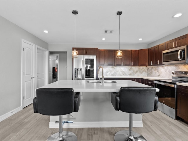 kitchen featuring appliances with stainless steel finishes, light wood-type flooring, light countertops, and a sink