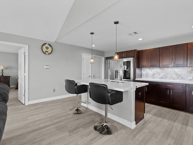 kitchen with visible vents, stainless steel fridge with ice dispenser, a breakfast bar area, light countertops, and backsplash