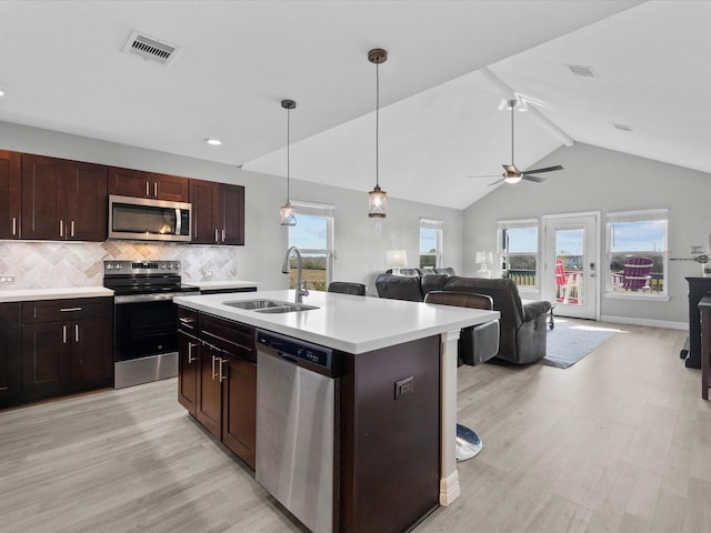 kitchen featuring appliances with stainless steel finishes, open floor plan, visible vents, and a sink