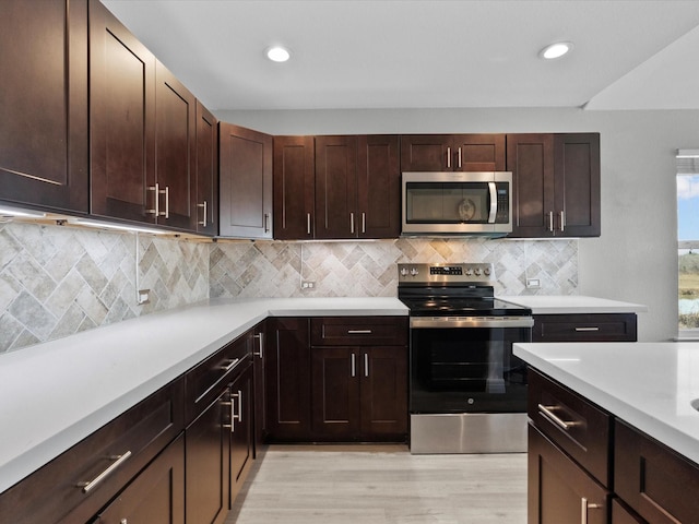 kitchen featuring appliances with stainless steel finishes, light wood-type flooring, light countertops, and backsplash