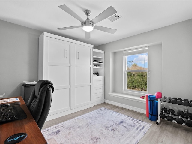 office space featuring light wood-type flooring, ceiling fan, visible vents, and baseboards