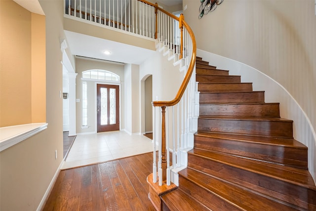 entryway with stairs, baseboards, a high ceiling, and hardwood / wood-style flooring