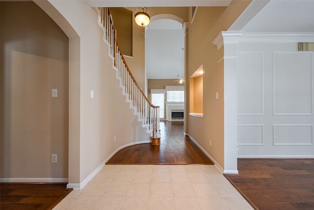 entrance foyer featuring arched walkways, a fireplace, wood finished floors, baseboards, and stairs