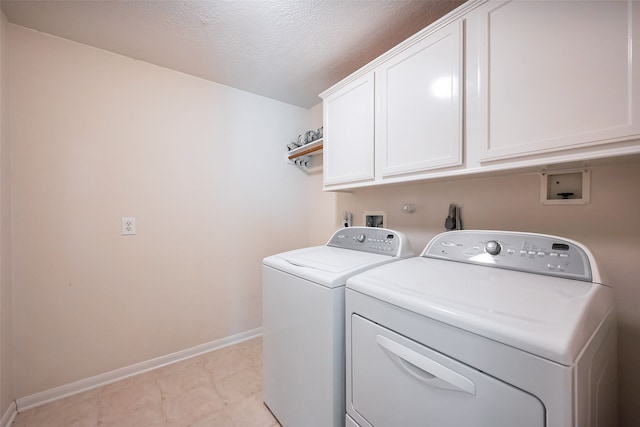 washroom with a textured ceiling, washing machine and clothes dryer, cabinet space, and baseboards