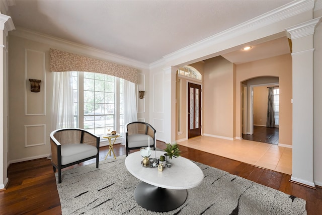 interior space with arched walkways, crown molding, dark wood finished floors, decorative columns, and baseboards