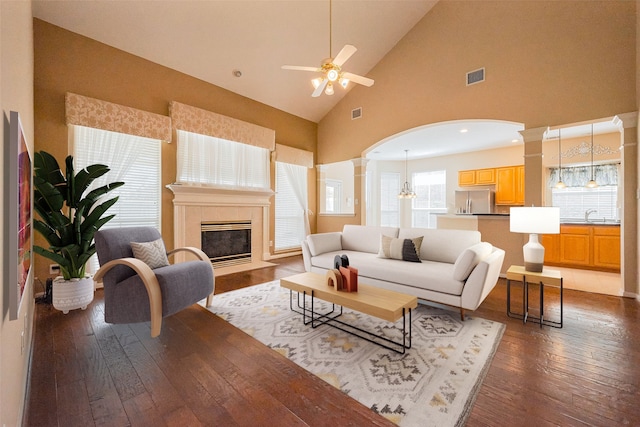 living room with decorative columns, a fireplace, visible vents, ceiling fan, and hardwood / wood-style flooring