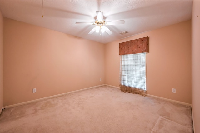 empty room with carpet floors, baseboards, visible vents, and a ceiling fan