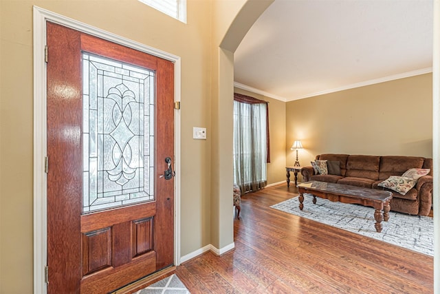 foyer featuring baseboards, arched walkways, wood finished floors, and ornamental molding