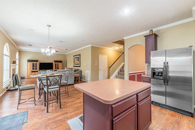 kitchen featuring a center island, arched walkways, a notable chandelier, light wood-type flooring, and stainless steel fridge with ice dispenser