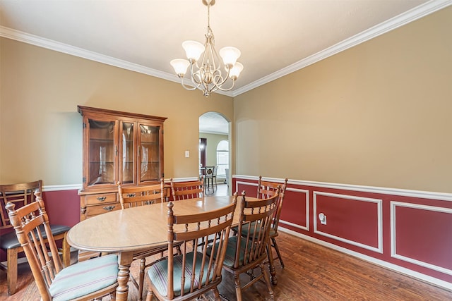 dining space featuring arched walkways, wainscoting, ornamental molding, wood finished floors, and a notable chandelier