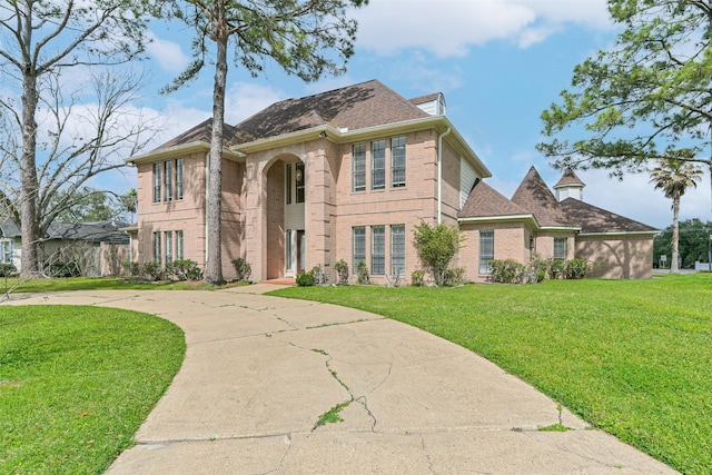 view of front of home featuring a front lawn, brick siding, and curved driveway