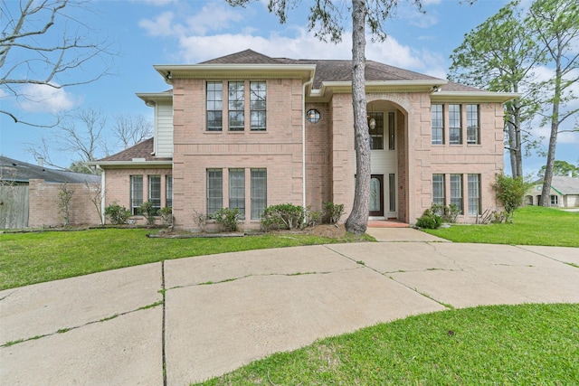 view of front of property with a shingled roof, a front lawn, and brick siding