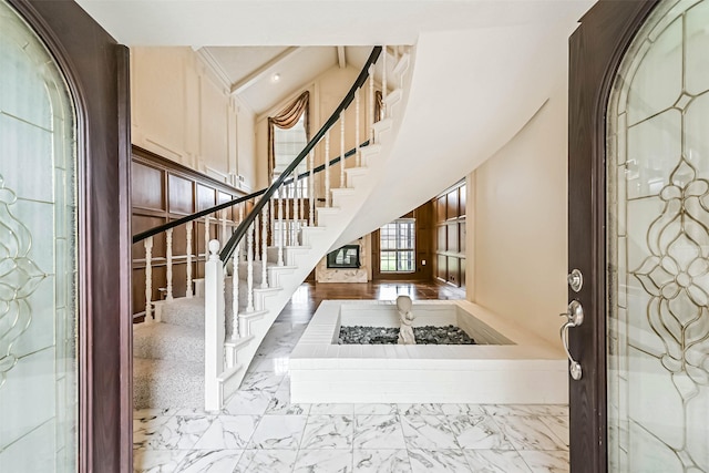 entryway featuring marble finish floor, a high ceiling, and stairs